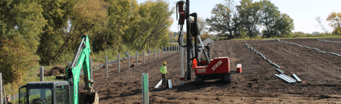 Pile driver machine pounding racking into the ground.