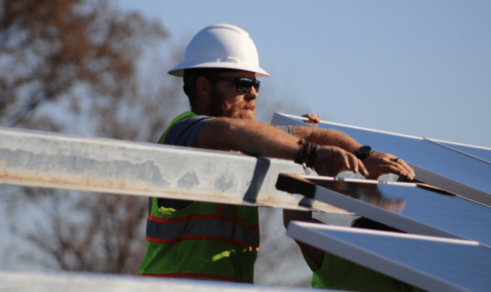 Commercial solar installer working on setting a solar module. 